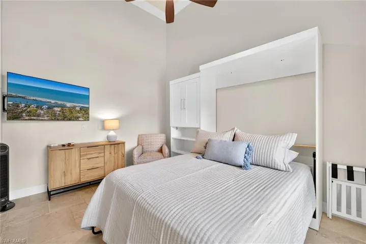 Bedroom featuring a high ceiling, a ceiling fan, and light stone finish flooring