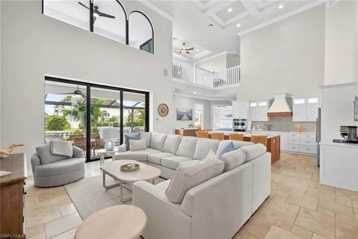 Living area featuring a high ceiling, stone tile floors, recessed lighting, ceiling fan, and ornamental molding