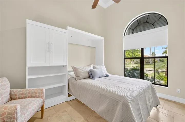 Bedroom with stone tile floors, a high ceiling, and ceiling fan