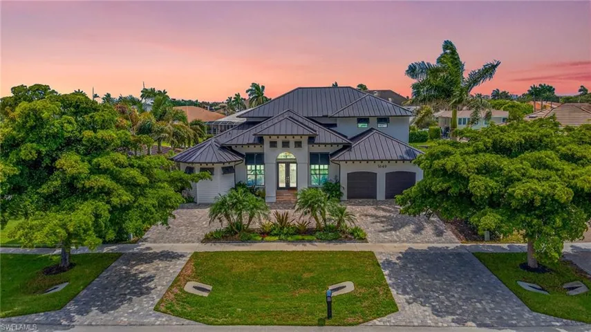 View of front facade with french doors, decorative driveway, a metal roof, a standing seam roof, and a front lawn