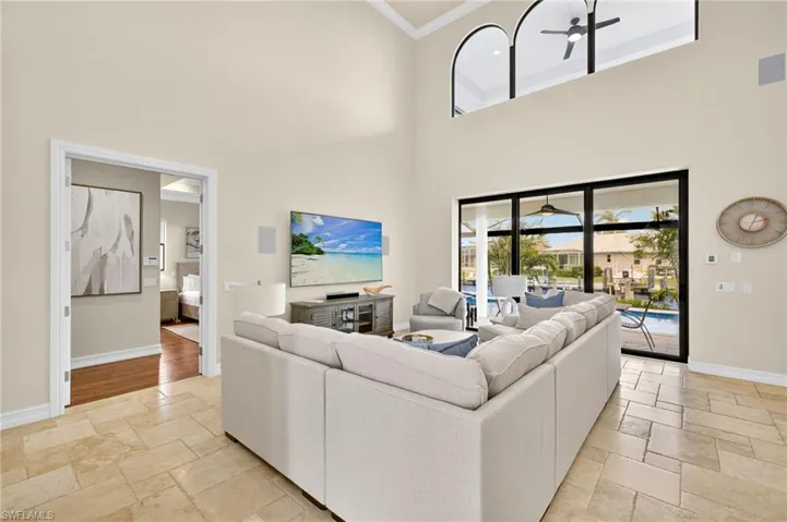 Living room with stone tile flooring, ceiling fan, a towering ceiling, and ornamental molding