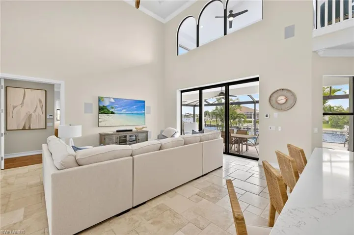 Living area with crown molding, a towering ceiling, and stone tile flooring