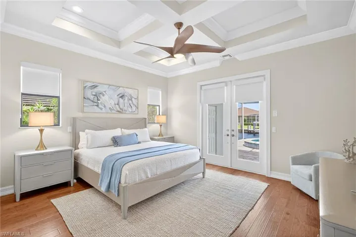 Bedroom featuring access to outside, light wood-style floors, coffered ceiling, crown molding, and french doors