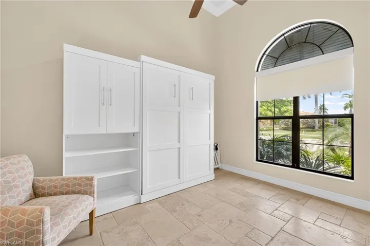 Sitting room with ceiling fan, stone tile floors, and a high ceiling