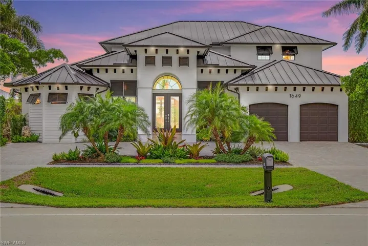 View of front of property featuring french doors, a standing seam roof, a metal roof, and a lawn