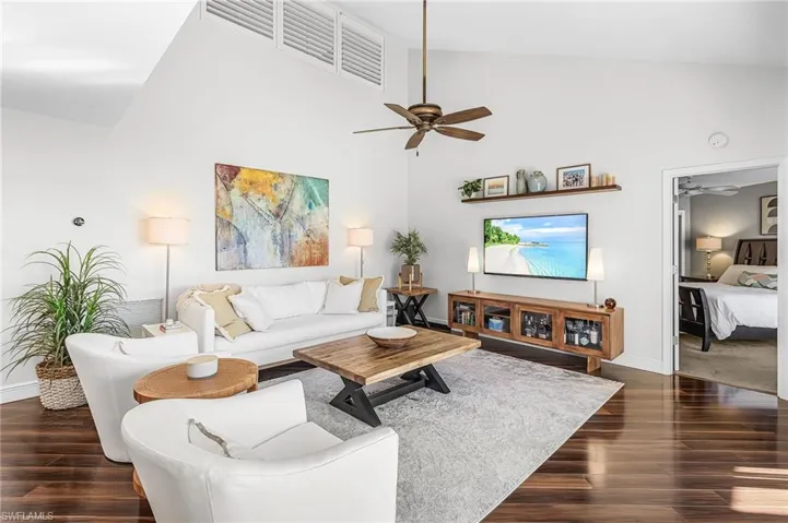 Spacious great room with dark wood-type flooring, ceiling fan, and high vaulted ceiling