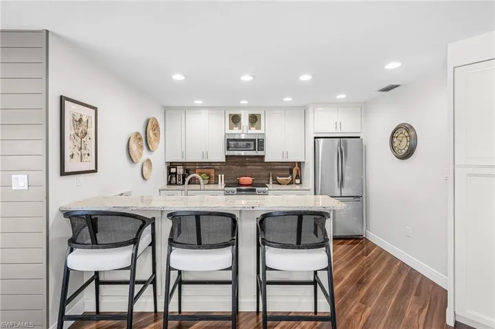 Kitchen featuring a breakfast bar, pantry cabinet, stainless steel appliances, and white cabinets.