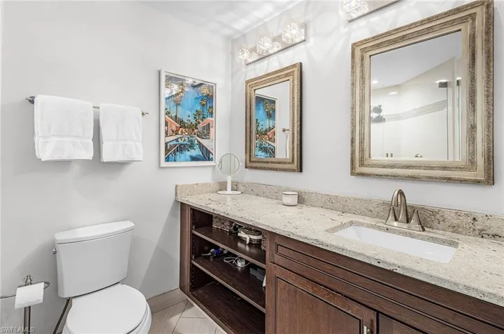 Owner's bath has plenty of counter top space and several storage options with open shelving, cabinets, and linen closet.