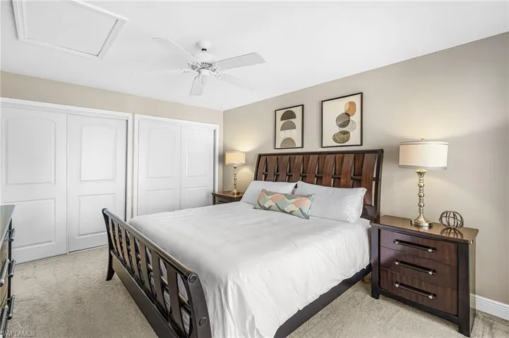 Owner's suite features two closets, light colored carpet, and a ceiling fan
