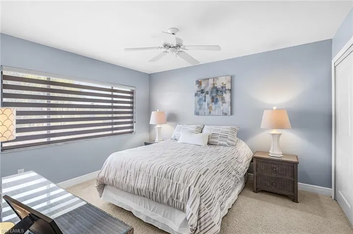 Guest bedroom with light colored carpet, two closets and a ceiling fan
