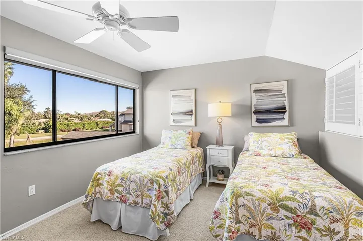 Upstairs guest bedroom featuring light colored carpet, ceiling fan, and vaulted ceiling