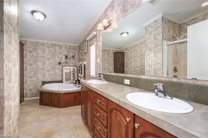 Bathroom featuring ornamental molding, dual vanity, tile flooring, and independent shower and bath