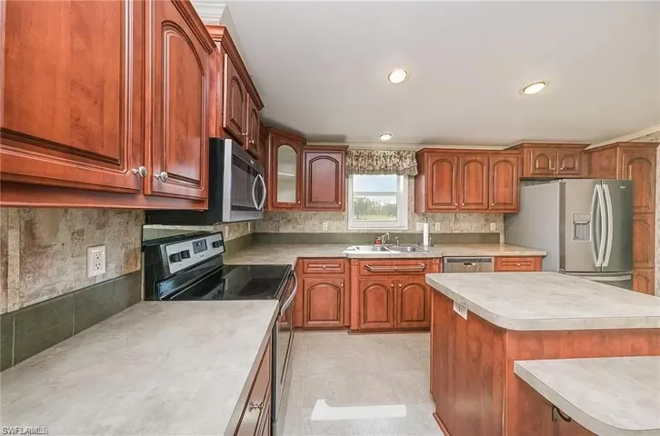 Kitchen with tasteful backsplash, light tile floors, a center island, sink, and appliances with stainless steel finishes