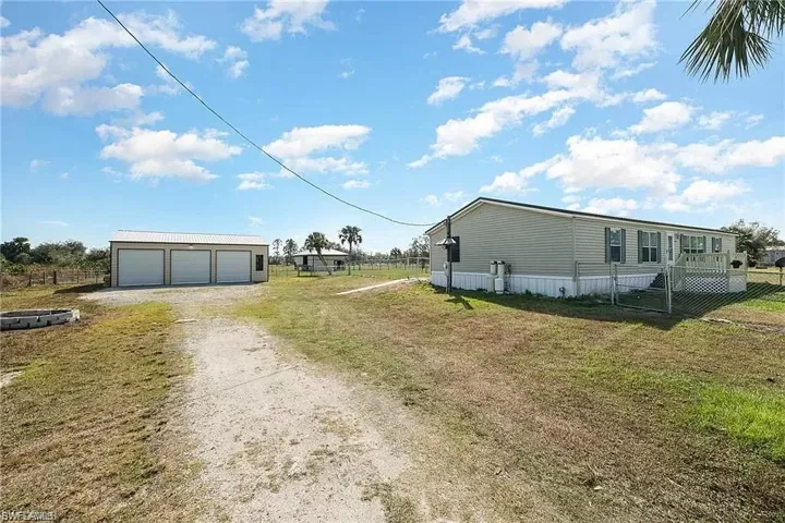 View of side of home featuring an outdoor structure, a garage, and a lawn