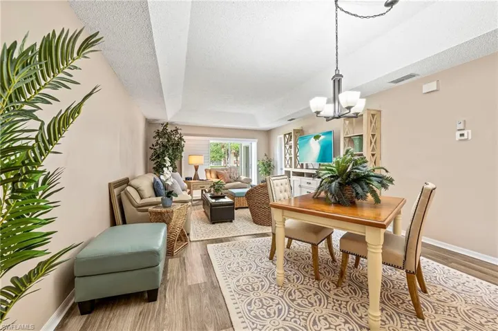 Dining space featuring a raised ceiling, a textured ceiling, light wood-style flooring, and a chandelier