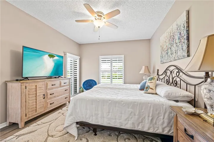 Bedroom with ceiling fan, light wood finished floors, and a textured ceiling