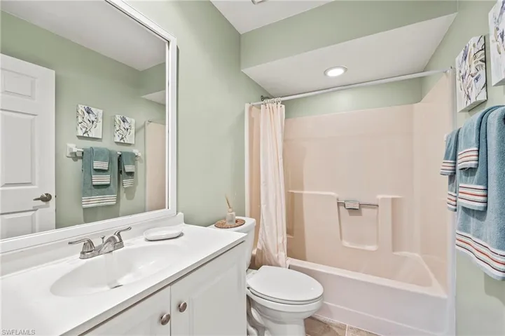 Full bath with shower / bath combo, vanity, recessed lighting, and tile patterned flooring