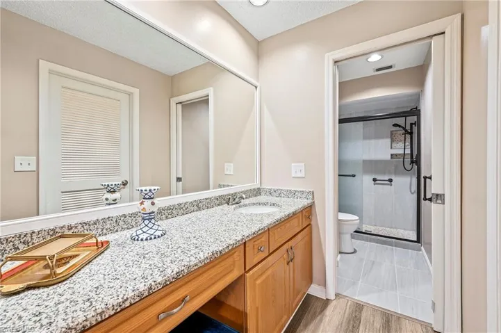 Bathroom featuring a stall shower, vanity, a textured ceiling, and light wood-type flooring