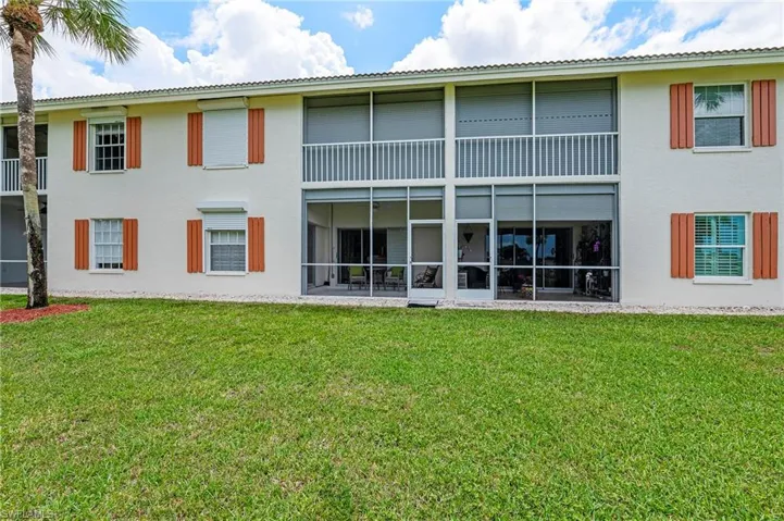 Back of house with a lawn, a sunroom, and a balcony