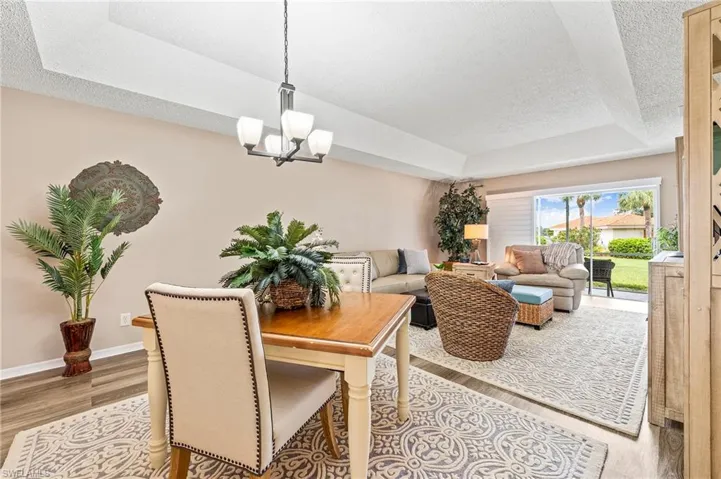 Dining room featuring a raised ceiling, a textured ceiling, wood finished floors, and a chandelier