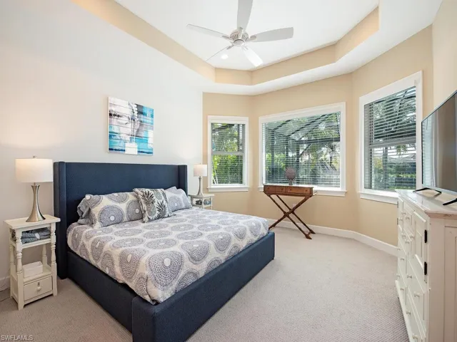 Primary bedroom with tray ceiling overlooking pool and screened Lanai.
