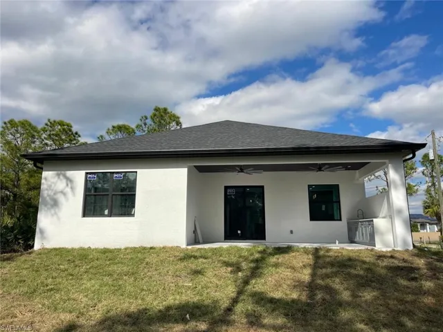 Back of property featuring a patio, ceiling fan, exterior kitchen, and a lawn