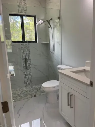 Bathroom featuring a shower with door, vanity, and toilet