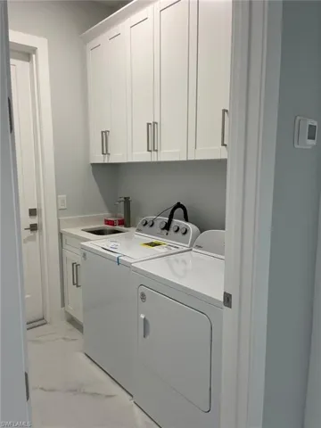 Laundry room featuring cabinets, washing machine and dryer, and sink