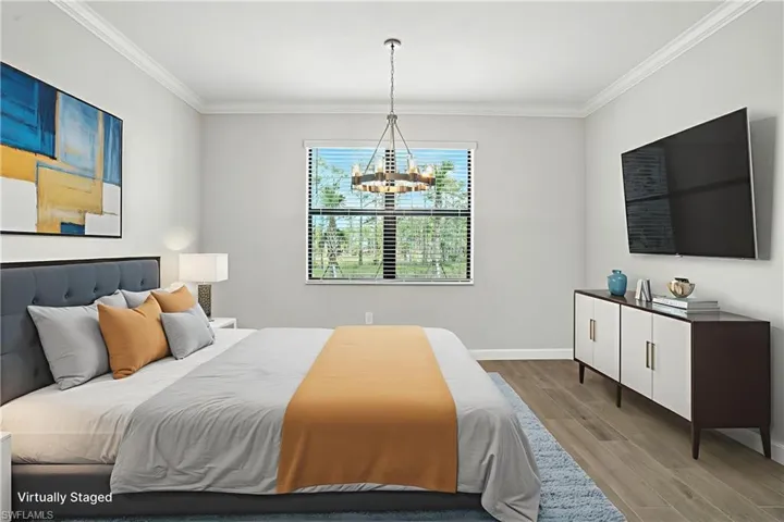 Bedroom with ornamental molding, wood finished floors, and a chandelier
