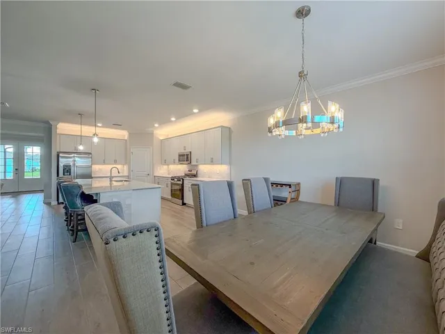 Dining room featuring crown molding, a chandelier, recessed lighting, french doors, and light wood-style floors