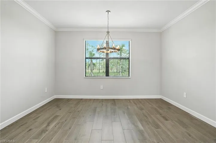 Unfurnished dining area featuring wood finished floors, crown molding, and a chandelier