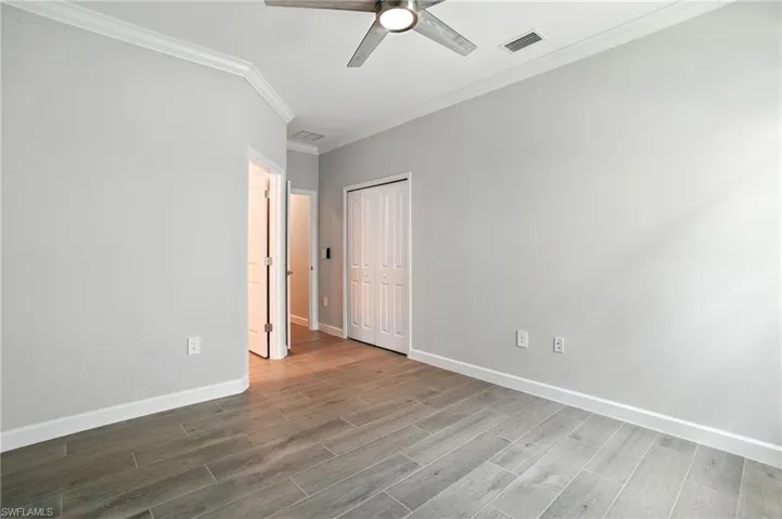 Unfurnished bedroom featuring light wood-style floors, ornamental molding, ceiling fan, and a closet