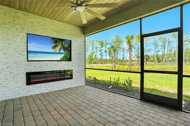 Unfurnished sunroom with a ceiling fan, a stone fireplace, and plenty of natural light
