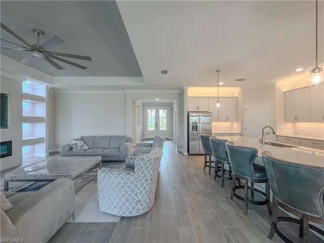 Living room featuring crown molding, wood finish floors, ceiling fan, french doors, and built in shelves