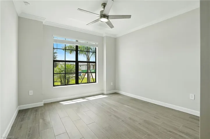 Unfurnished room featuring crown molding, light wood-style flooring, and ceiling fan
