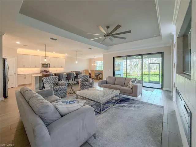 Living room featuring crown molding, ceiling fan, a tray ceiling, a fireplace, and recessed lighting