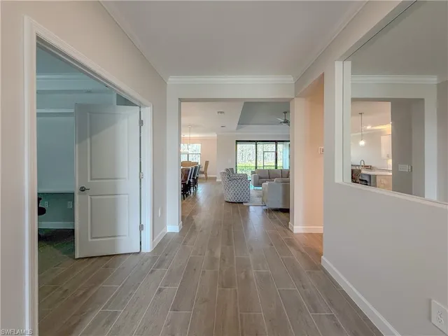 Hall with wood finish floors and crown molding