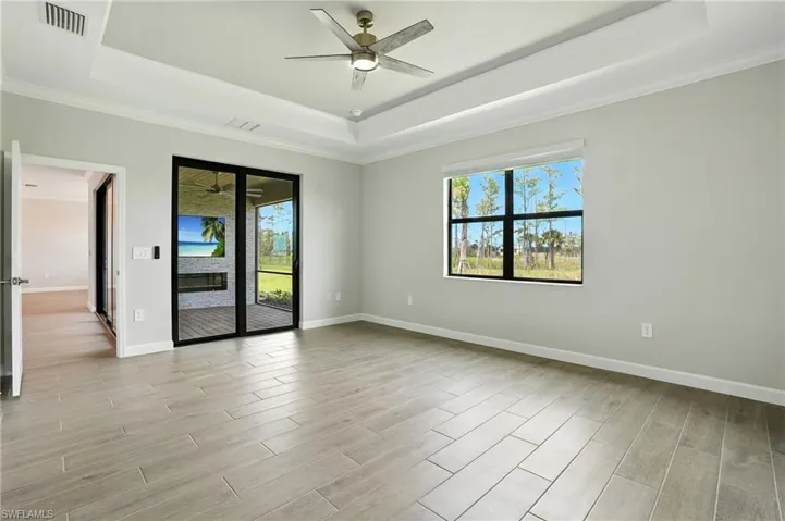 Spare room with a tray ceiling, ornamental molding, healthy amount of natural light, and light wood-type flooring