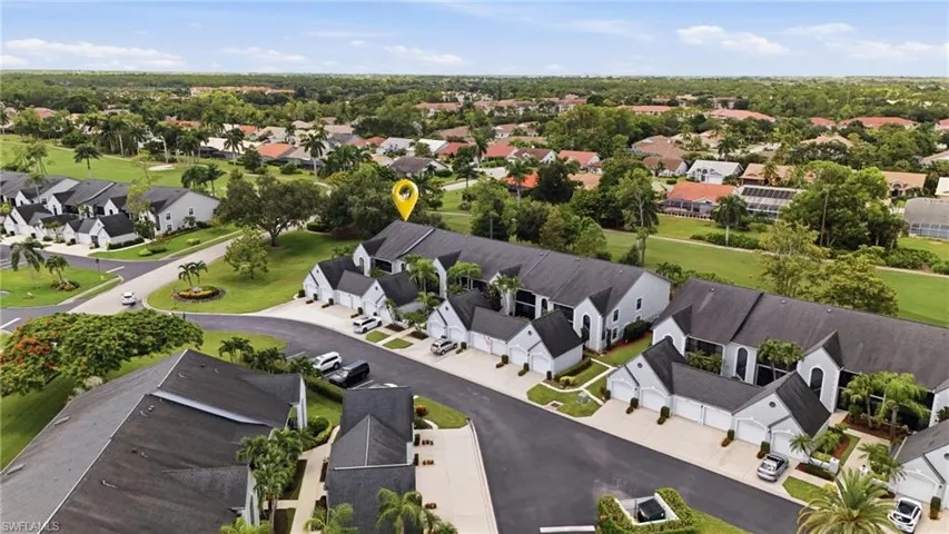 Multiple-unit residential structure with attached garages, surrounded by mature landscaping and a paved driveway