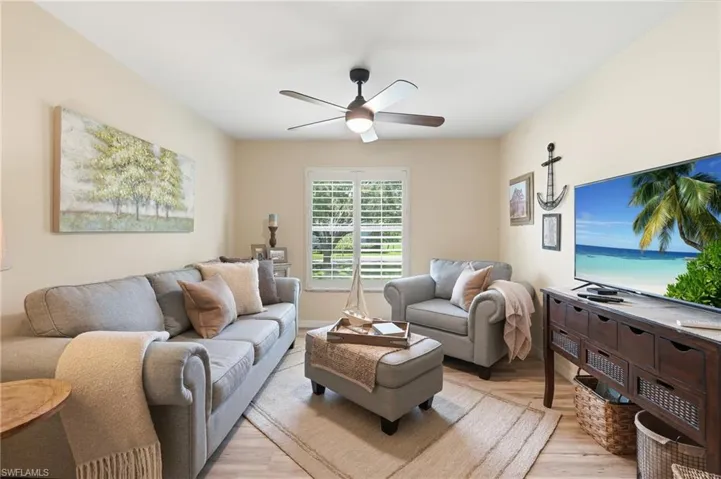 Neutral wall finishes, wood-finish flooring, plantation shutters, and a ceiling fan with integrated lighting