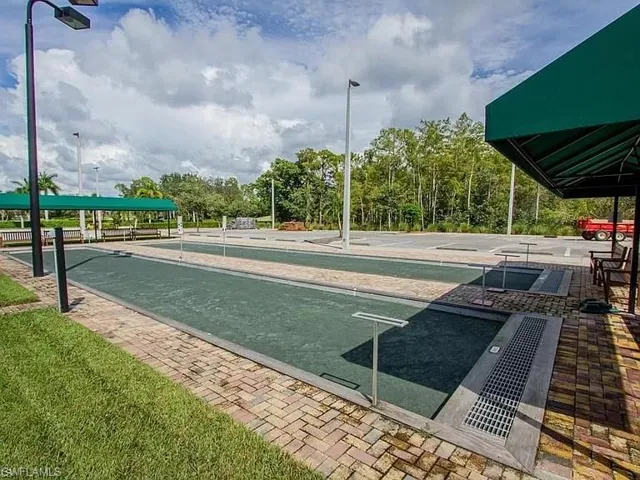 Two bocce ball courts with paved brick surrounds, covered seating areas, and adjacent paved parking