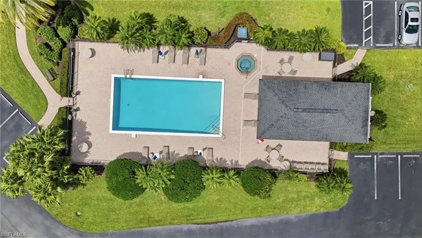 Community swimming pool with an adjacent spa, a paver patio surround, a covered pavilion, and surrounding landscaping