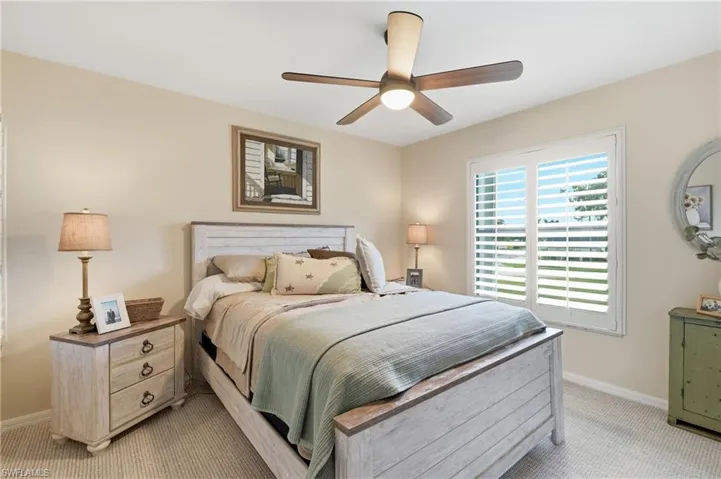 Carpeted room featuring a ceiling fan with integrated lighting, window with plantation shutters, and light-toned walls