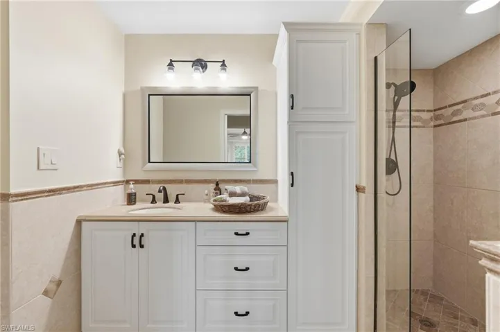 White vanity with integrated sink, stone countertop, and dark bronze hardware