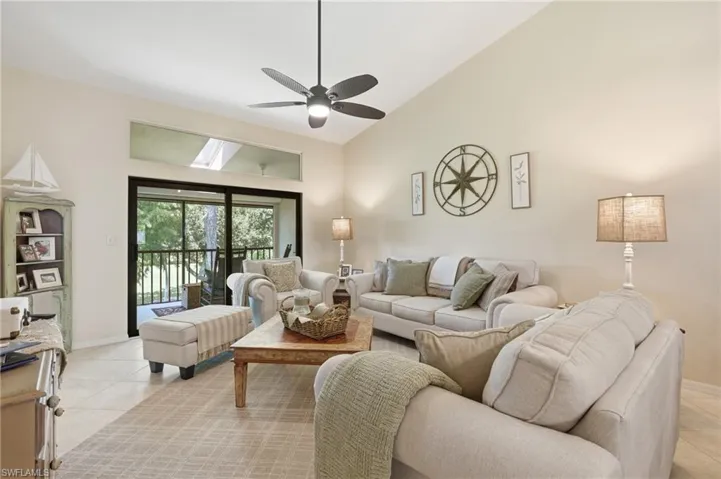 Vaulted ceiling with a ceiling fan, sliding glass doors to outdoor space, transom windows, and tile flooring