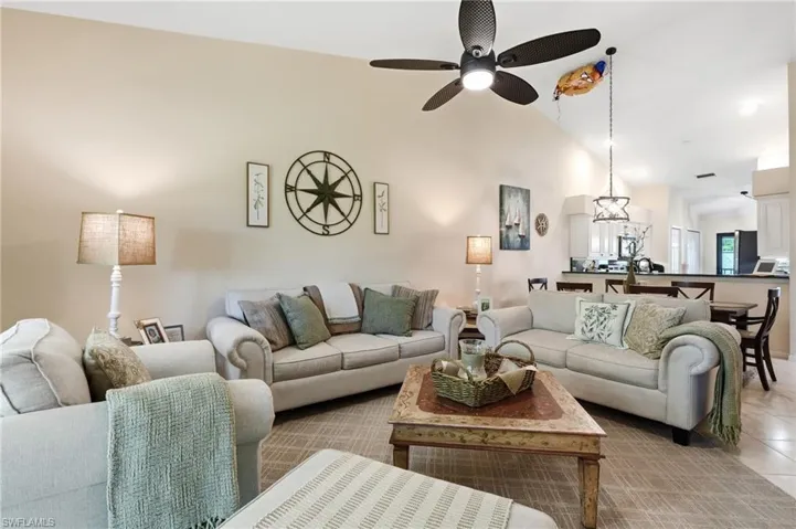 Vaulted ceiling, ceiling fan, recessed lighting, tile flooring, and integrated kitchen bar seating