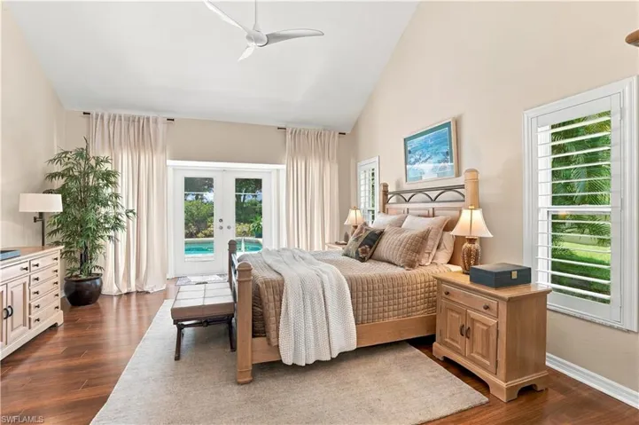 Spacious primary bedroom with wood flooring and direct lanai/pool access.