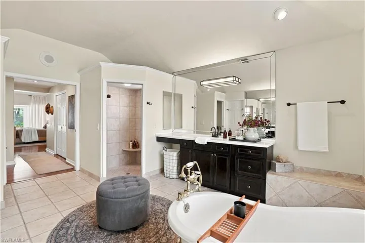 The primary bath features warm wood cabinetry, a freestanding soaking tub, and a spacious walk-in shower, creating a comfortable, spa-like retreat.