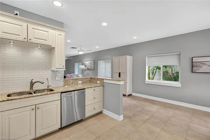 Kitchen with light stone countertops, decorative backsplash, stainless steel dishwasher, healthy amount of natural light, and recessed lighting