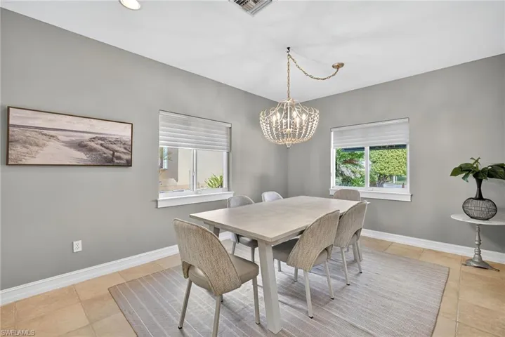 Dining room with light tile patterned floors, healthy amount of natural light, and a chandelier
